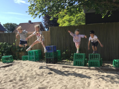 Børn der hopper i sandkassen sammen
